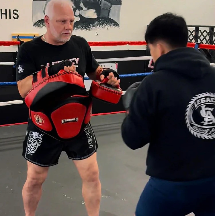 Coach Chris Sawtelle holding pads in the ring at Legacy Striking Academy